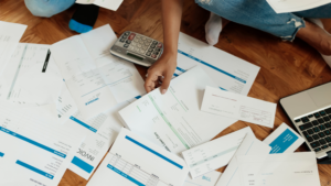 Business owner reviewing invoices, bills, and a calculator to understand business debt before selling a company