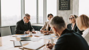 Executives in a boardroom meeting reviewing financial reports with a private equity or strategic buyer